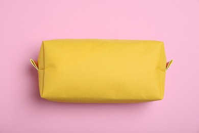 Photo of Yellow cosmetic bag on pink background, top view