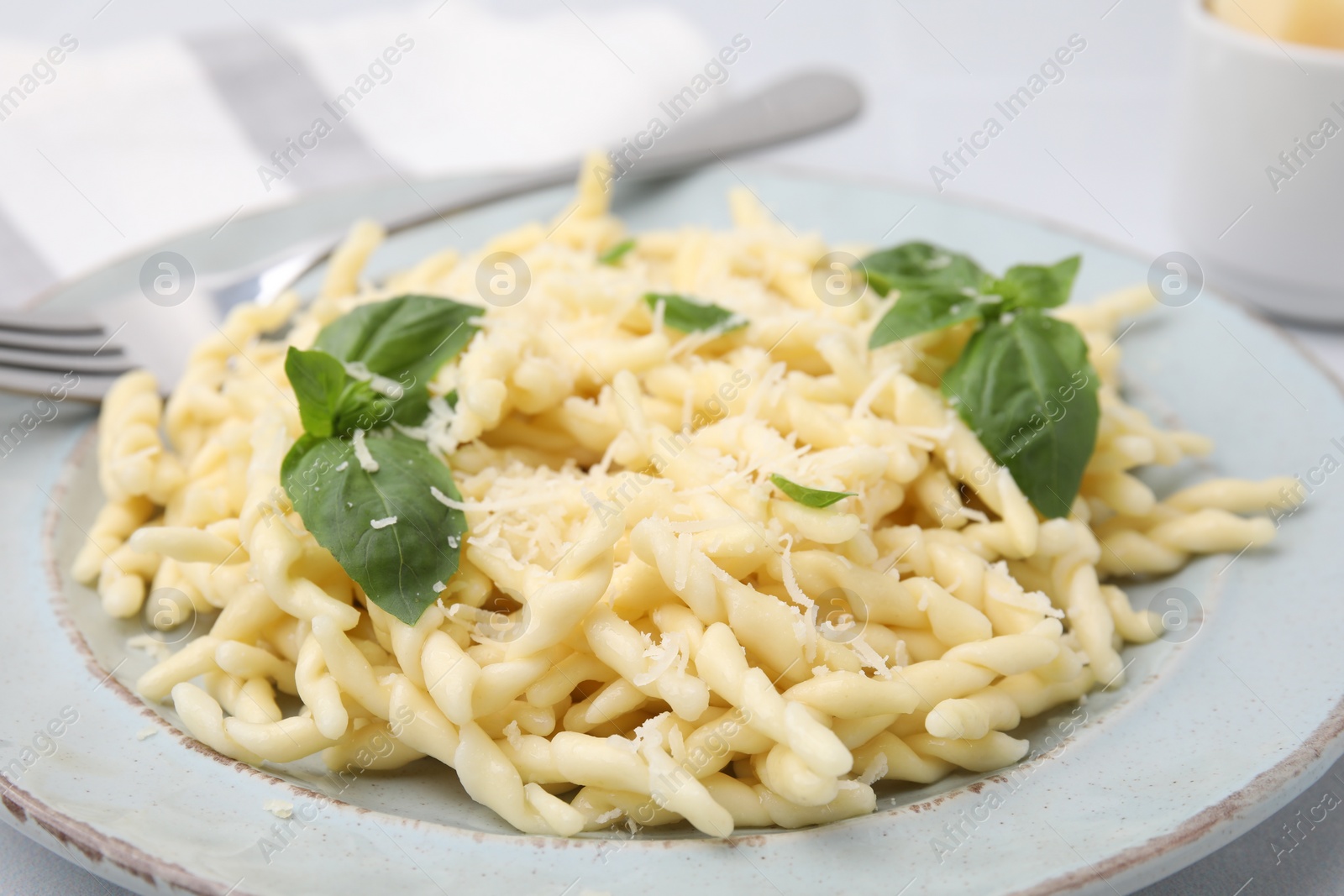 Photo of Plate of delicious trofie pasta with cheese and basil leaves on table, closeup