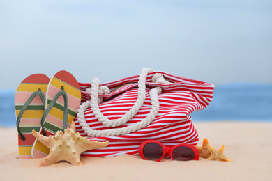 Photo of Bag and beach objects on sand near sea
