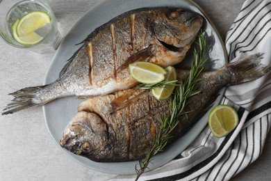 Delicious baked fish served with rosemary and lime on grey table, flat lay. Seafood