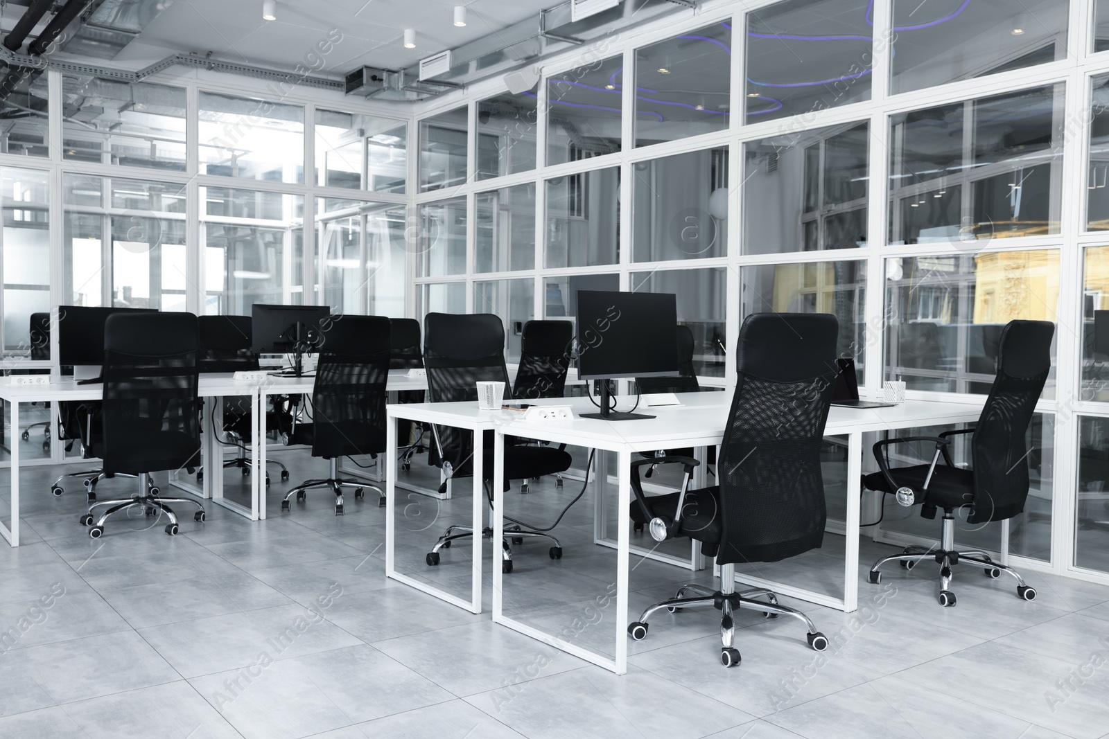 Photo of Stylish interior of open plan office. Workspace with computers, tables and chairs