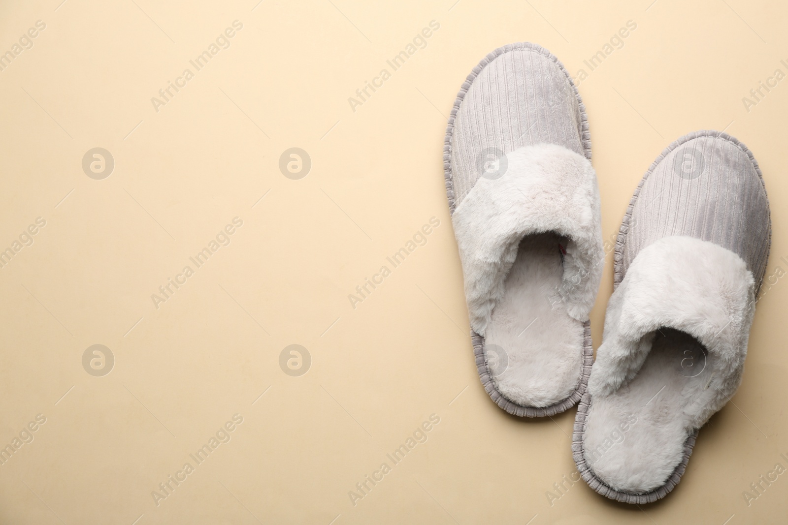 Photo of Pair of soft slippers on beige background, flat lay. Space for text