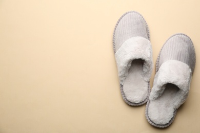 Photo of Pair of soft slippers on beige background, flat lay. Space for text