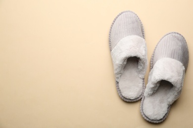 Pair of soft slippers on beige background, flat lay. Space for text