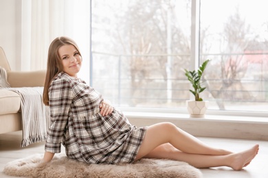 Beautiful pregnant woman sitting on floor at home