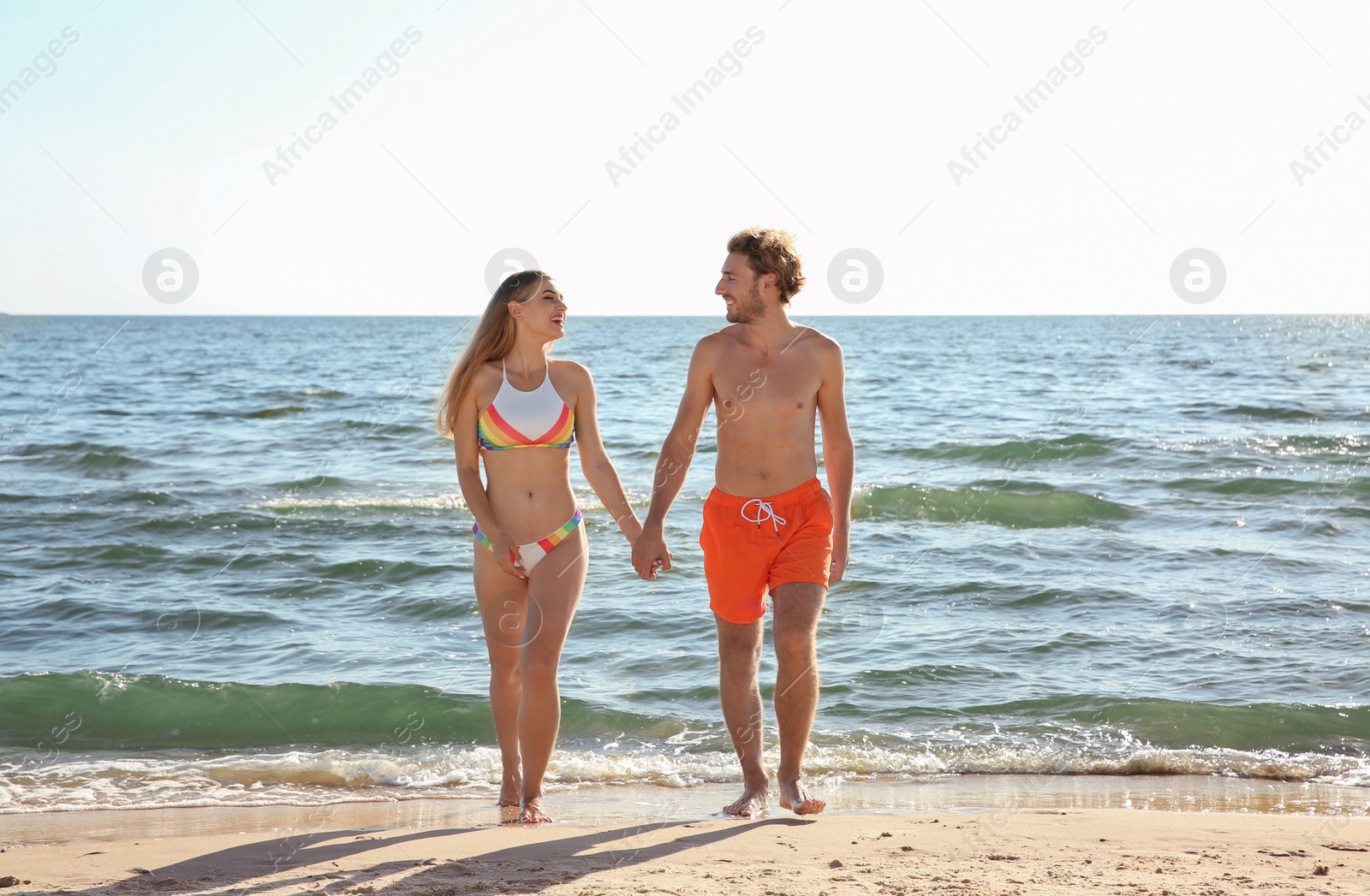 Photo of Happy young couple in beachwear posing on seashore