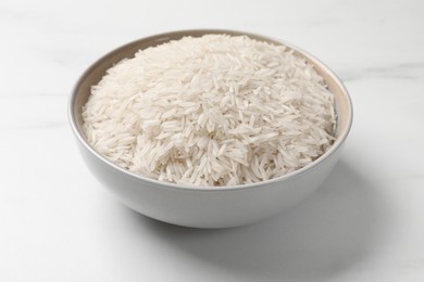 Photo of Raw basmati rice in bowl on white marble table