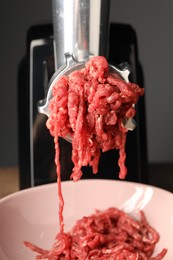 Electric meat grinder with beef mince on table, closeup