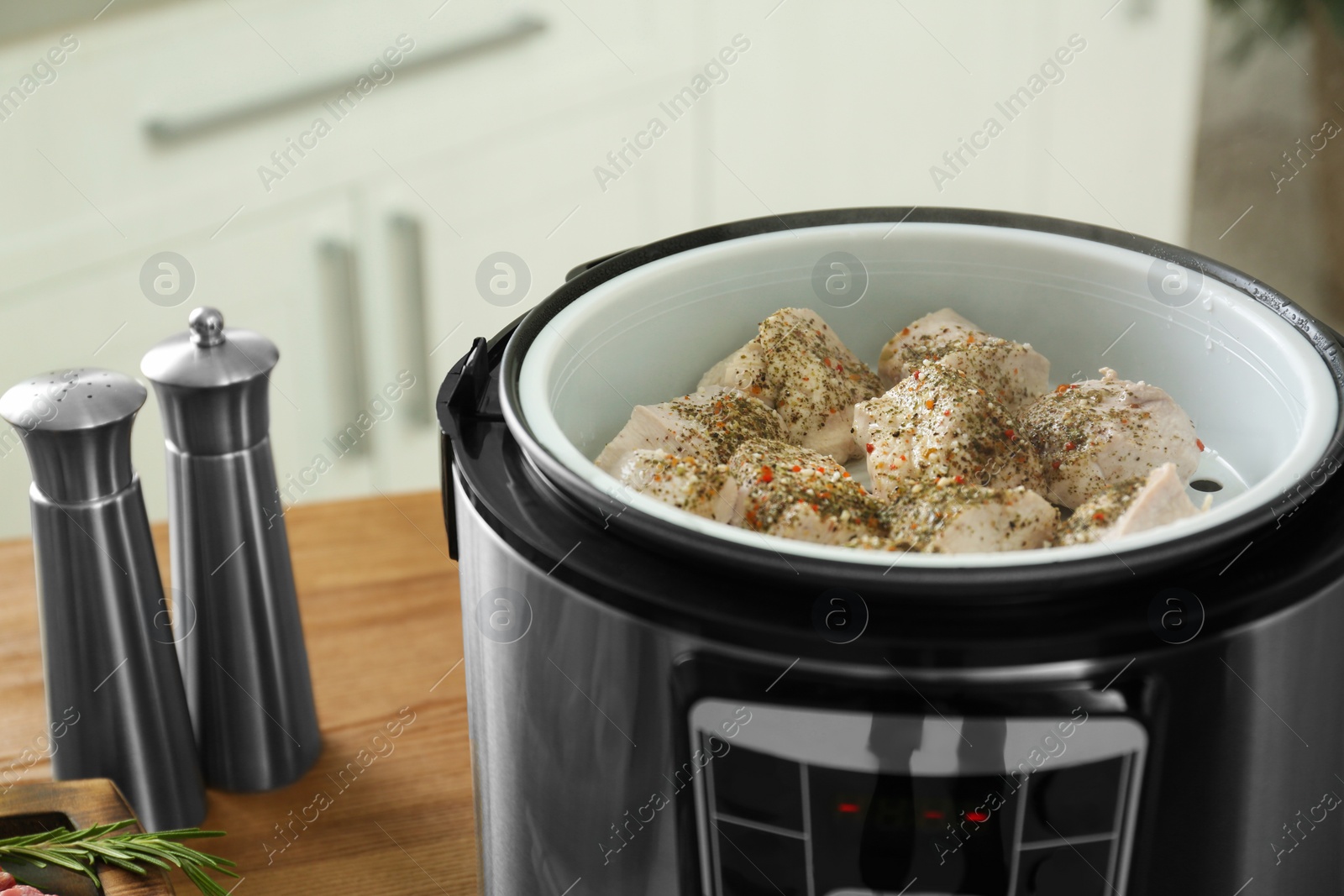Photo of Delicious chicken with spices in modern multi cooker on wooden table