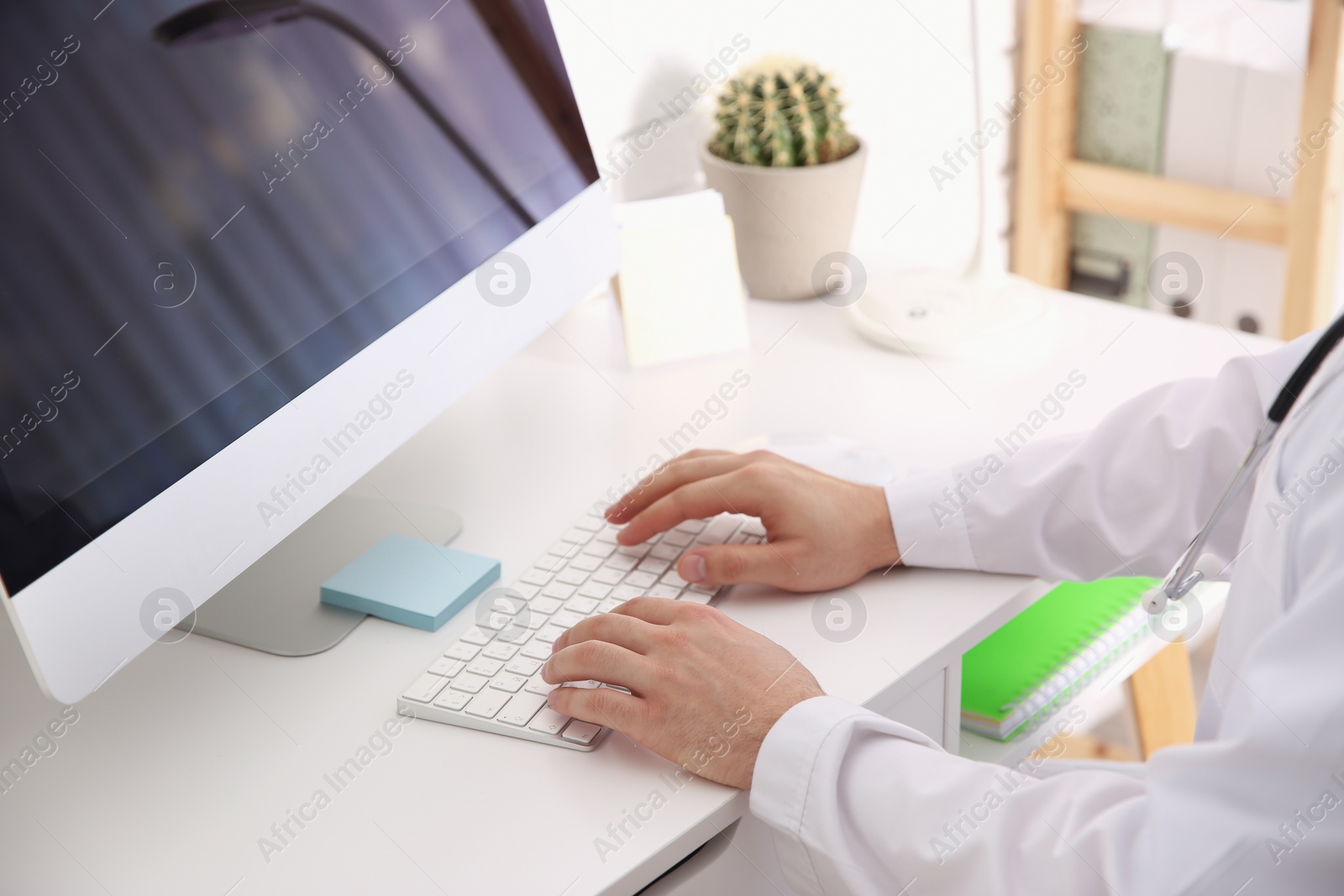 Photo of Doctor working with computer at desk in office, closeup