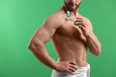 Photo of Man applying lotion onto his shoulder on green background, closeup