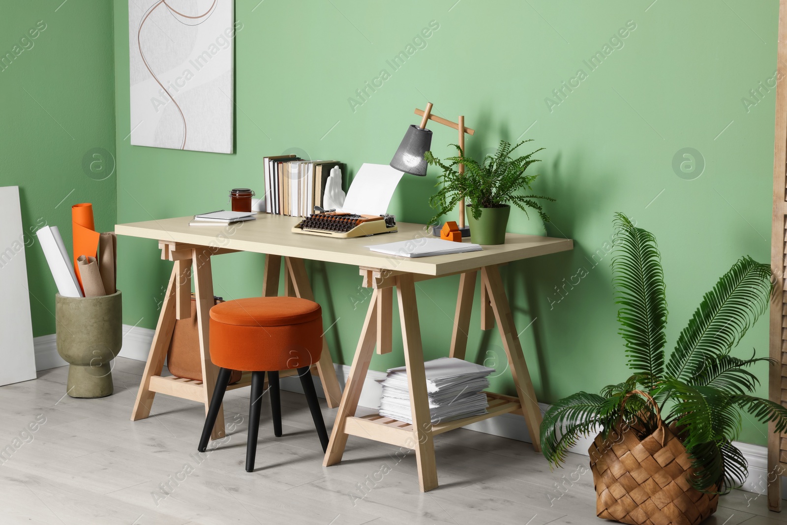 Photo of Writer's workplace with typewriter on wooden desk near pale green wall in room