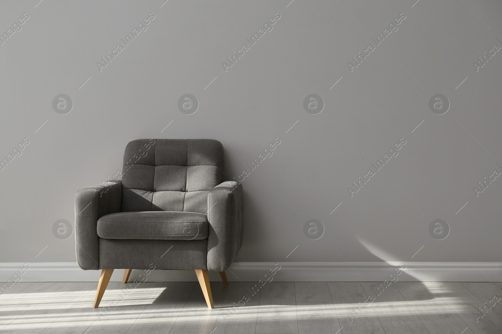 Photo of Stylish armchair near grey wall, space for text.  Interior element
