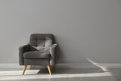 Stylish armchair near grey wall, space for text.  Interior element