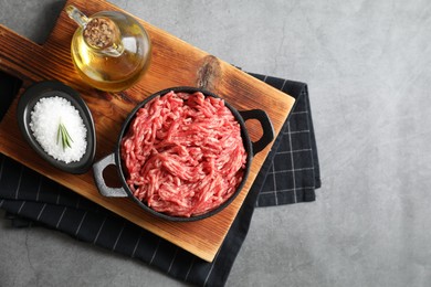 Photo of Raw ground meat in bowl, salt and oil on grey table, top view. Space for text