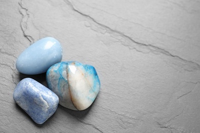 Photo of Beautiful natural blue gemstones on grey table, space for text