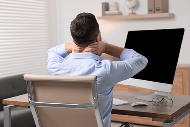 Photo of Man massaging stiff neck in office, back view