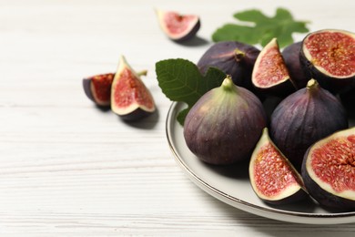 Whole and cut ripe figs on white wooden table, closeup. Space for text