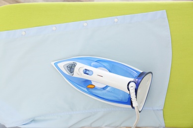 Photo of Modern iron on light fabric, top view. Laundry day