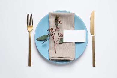 Stylish setting with cutlery, eucalyptus leaves and blank card on white background, top view. Space for text