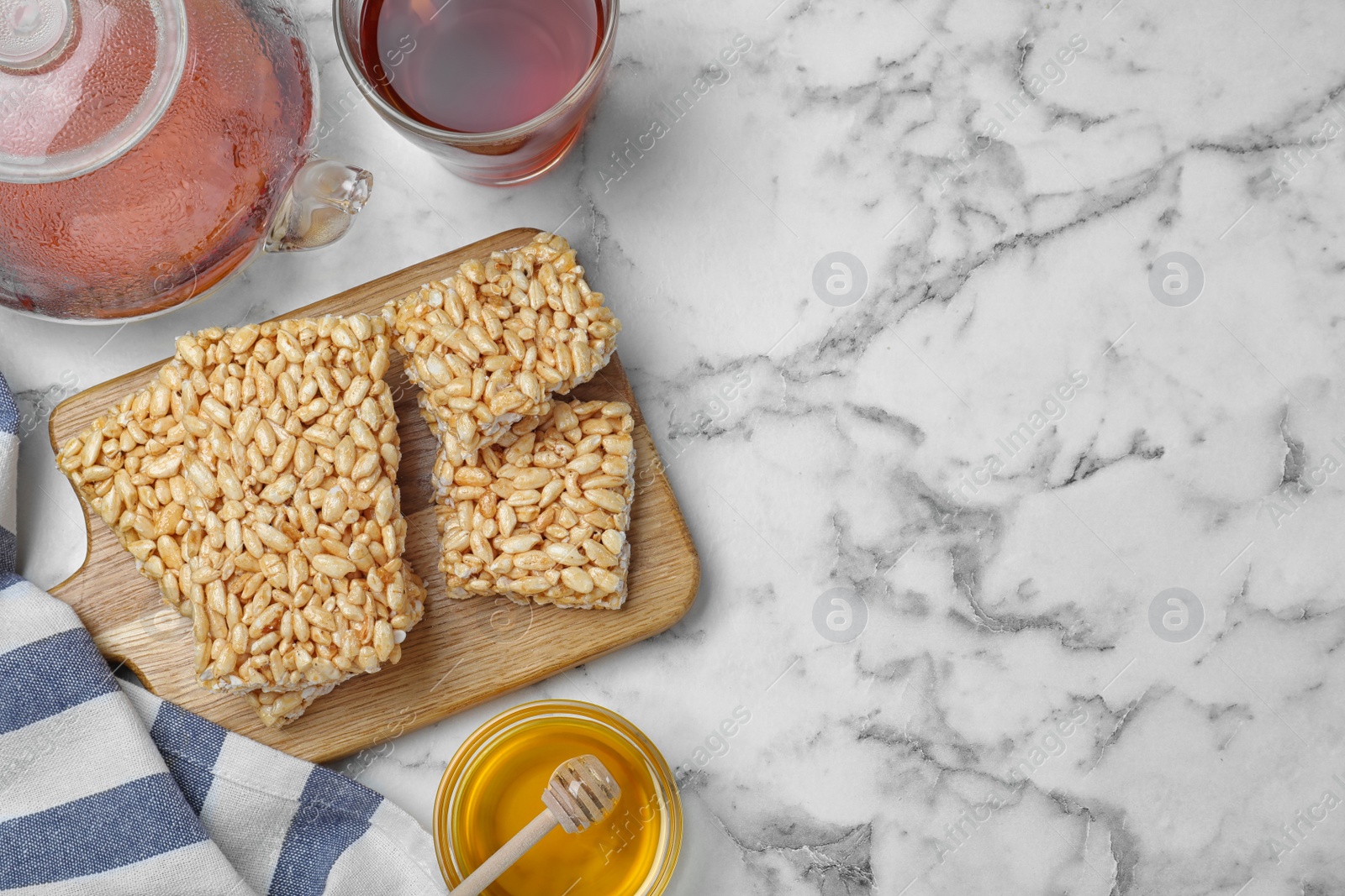 Photo of Delicious rice crispy treats on white marble table, flat lay. Space for text