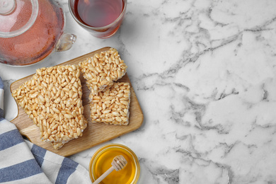 Photo of Delicious rice crispy treats on white marble table, flat lay. Space for text