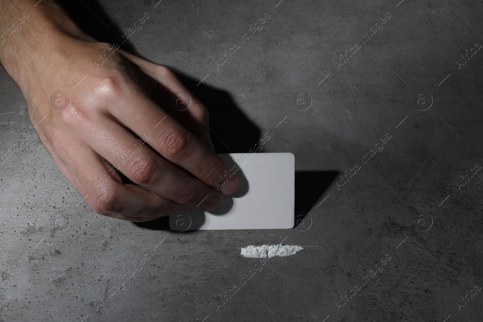 Photo of Addicted man preparing drugs for consumption at grey table, closeup