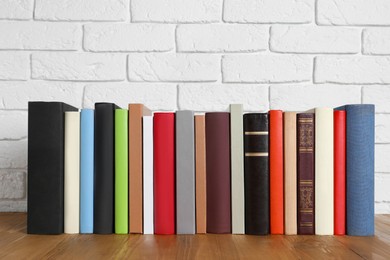 Photo of Books on wooden table near white brick wall