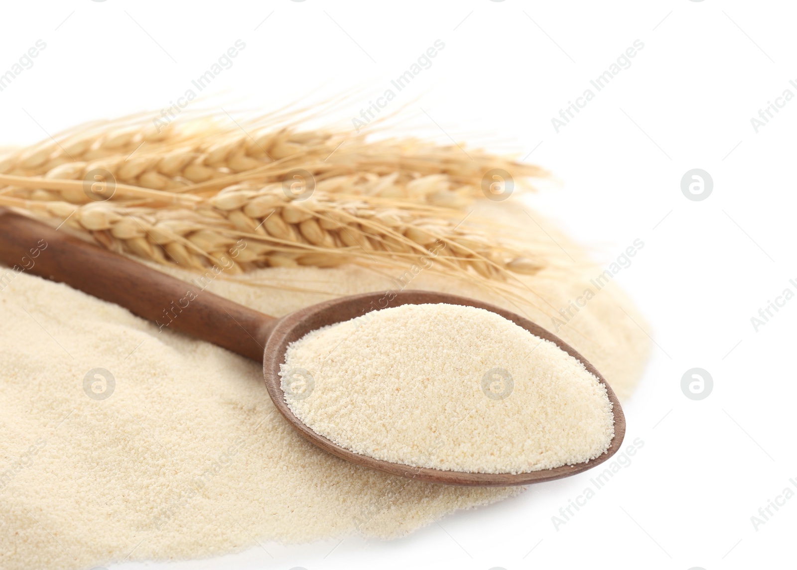 Photo of Spoon with semolina and spikelets on white background