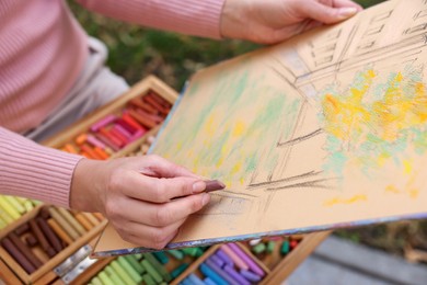 Photo of Woman drawing with soft pastels outdoors, closeup