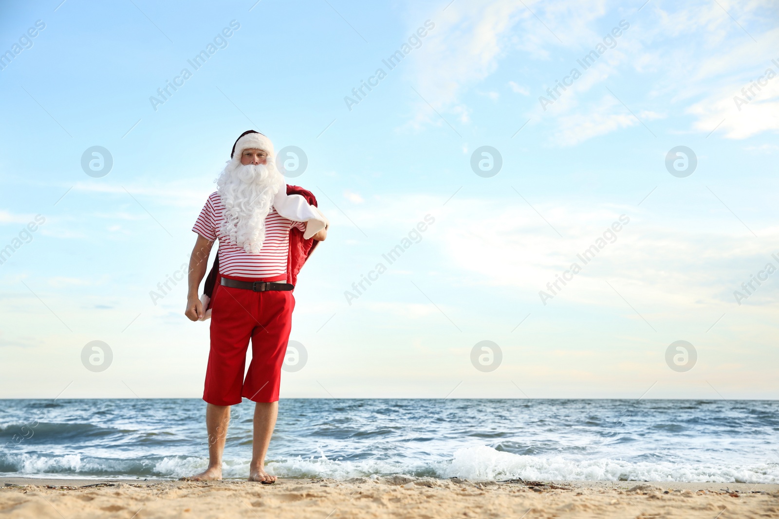 Photo of Santa Claus having fun on beach, space for text. Christmas vacation