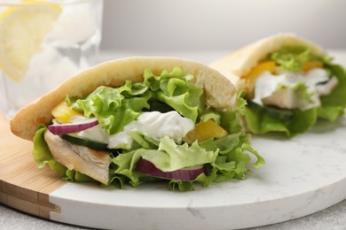 Delicious pita sandwiches with chicken breast and vegetables on board, closeup