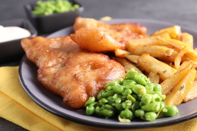 Photo of Tasty fish, chips and peas on table, closeup