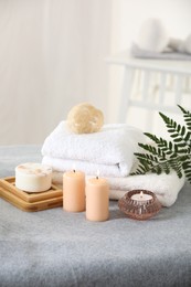 Photo of Spa composition. Burning candles, soap, towels and loofah on soft grey surface