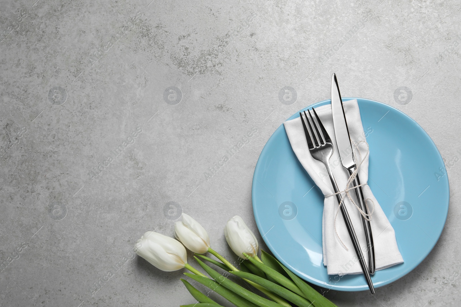 Photo of Stylish table setting with cutlery and flowers on grey background, flat lay. Space for text