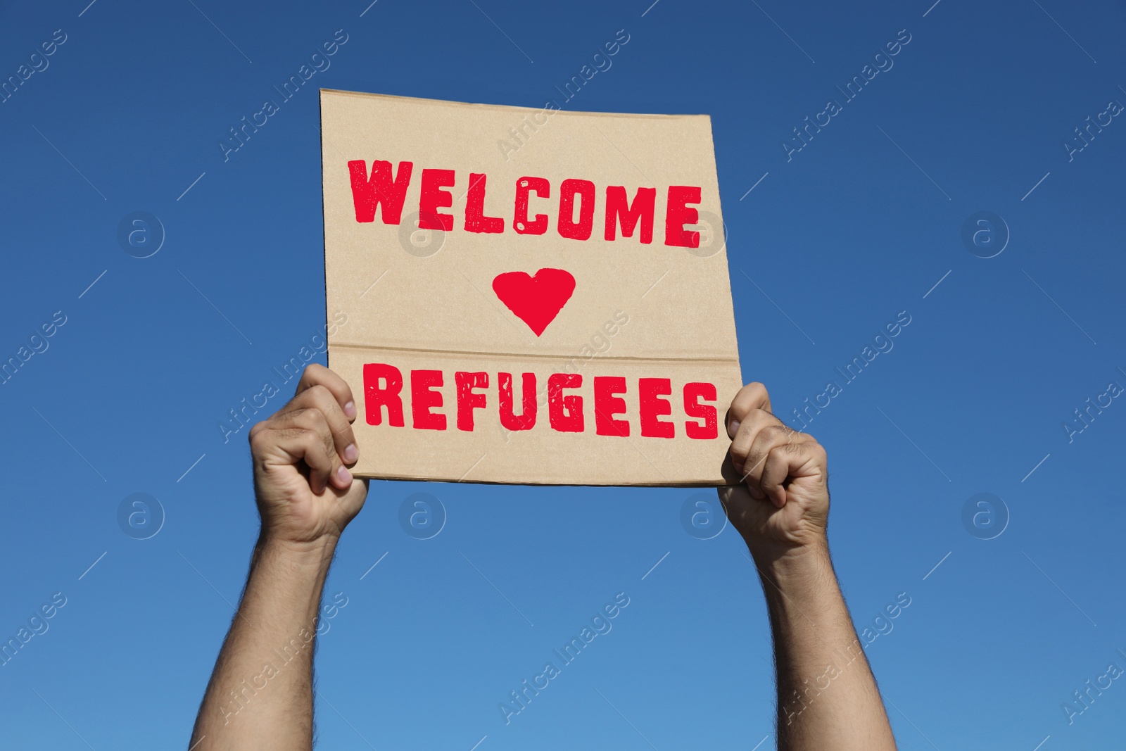 Image of Man holding poster with phrase WELCOME REFUGEES outdoors, closeup