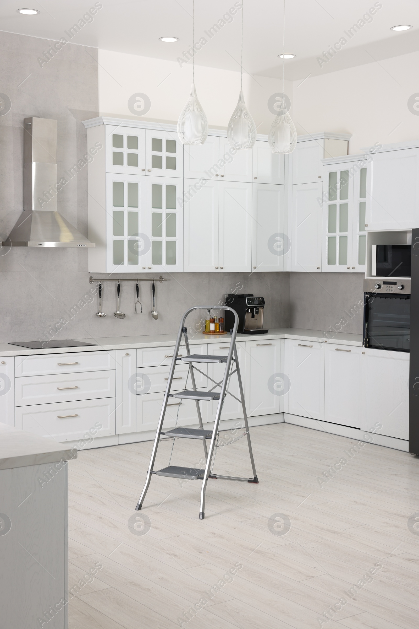 Photo of New metal stepladder on floor in kitchen