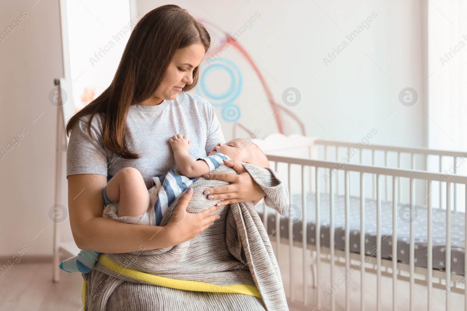 Photo of Mother with her sleeping baby near crib at home