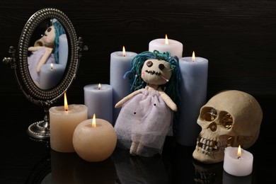 Voodoo doll pierced with pins and candles on black table. Curse ceremony