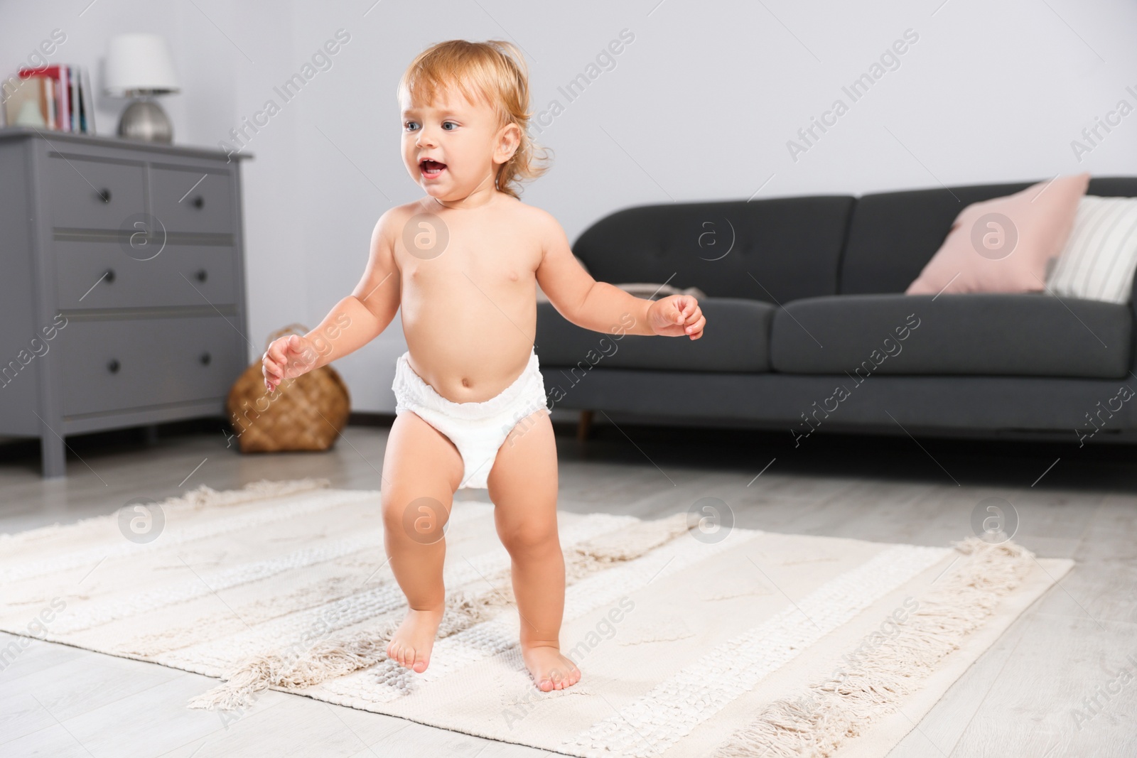 Photo of Cute baby learning to walk in living room