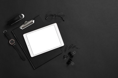 Photo of Modern tablet, stationery, wristwatch and glasses on black background, flat lay. Space for text