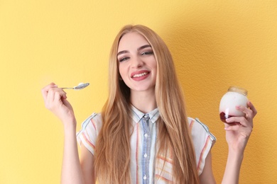 Young woman with yogurt on color background