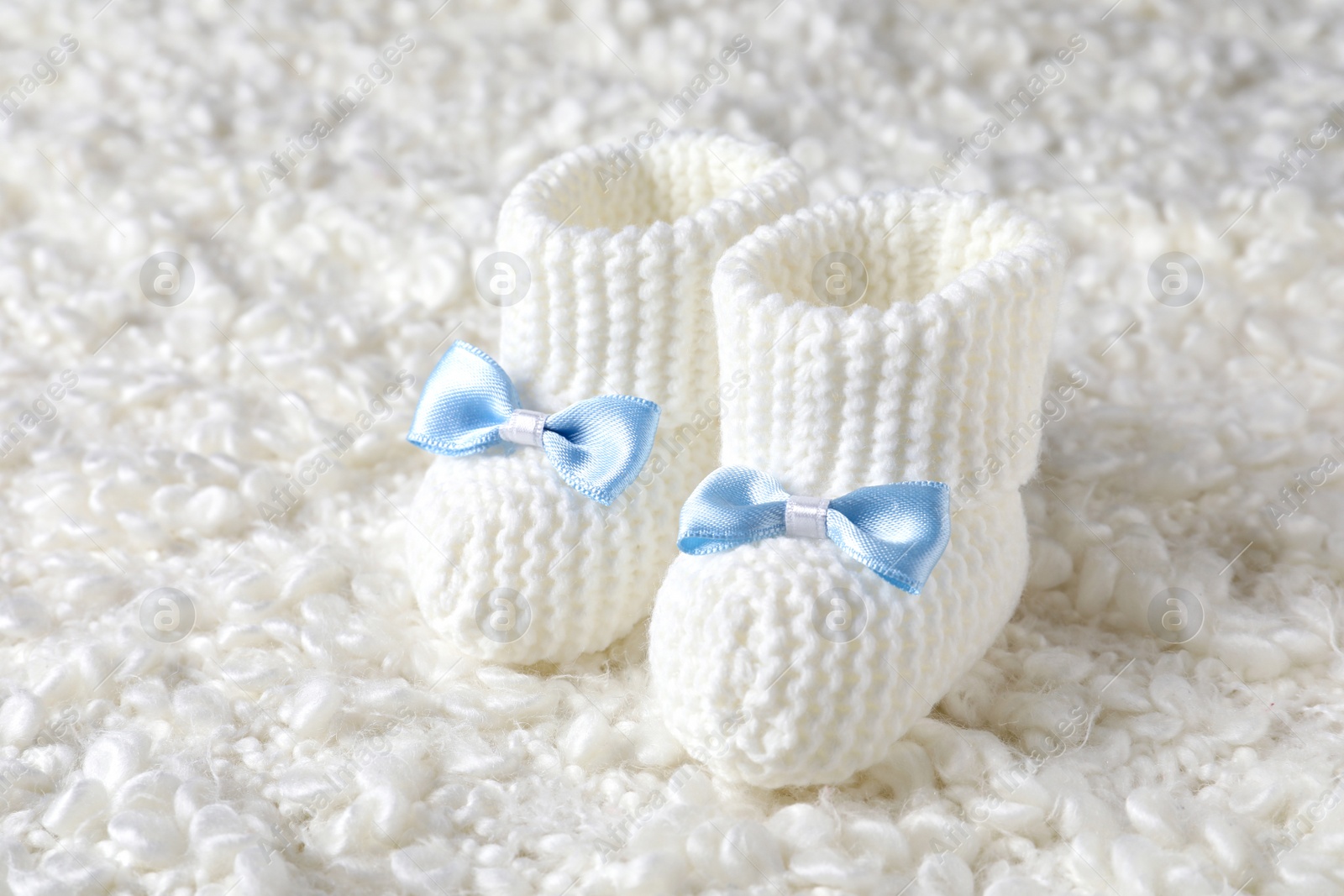 Photo of Handmade baby booties on soft light plaid