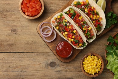 Photo of Tasty tacos with vegetables on wooden table, flat lay. Space for text