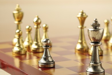 Photo of Chessboard with game pieces on beige background, closeup