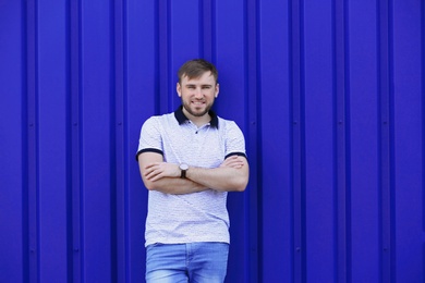 Young hipster man in stylish jeans posing near color wall