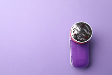 Photo of Modern fabric shaver to remove lint on purple background, top view. Space for text