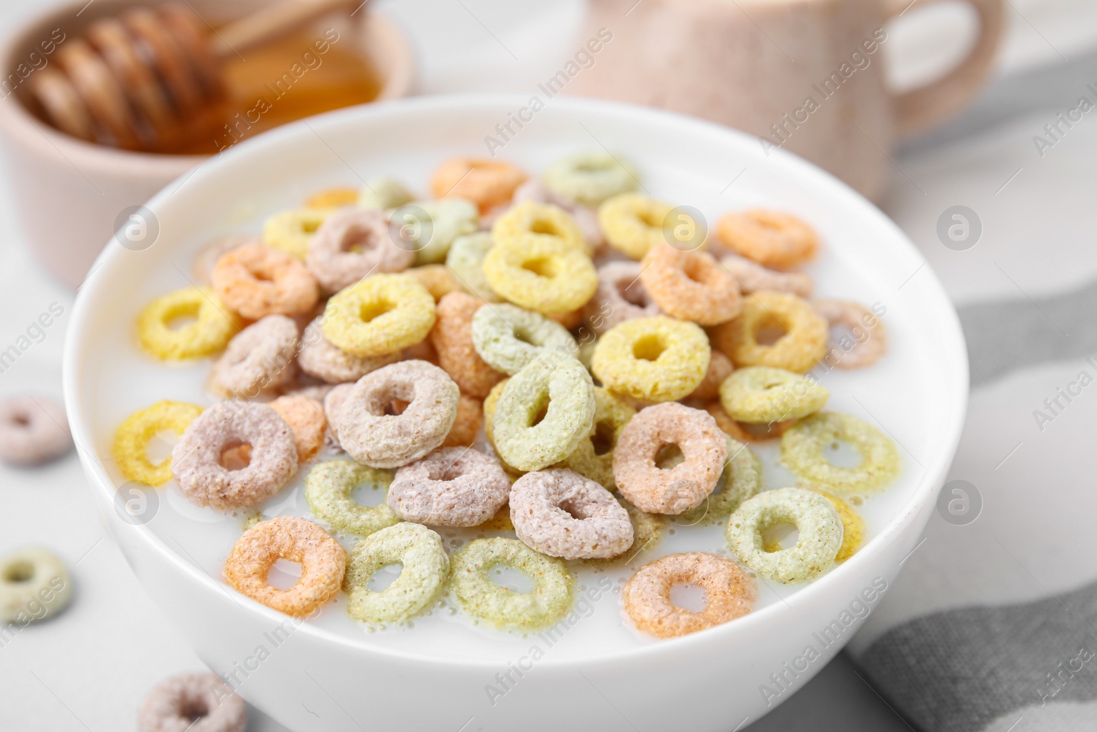 Photo of Cereal rings and milk in bowl on table, closeup