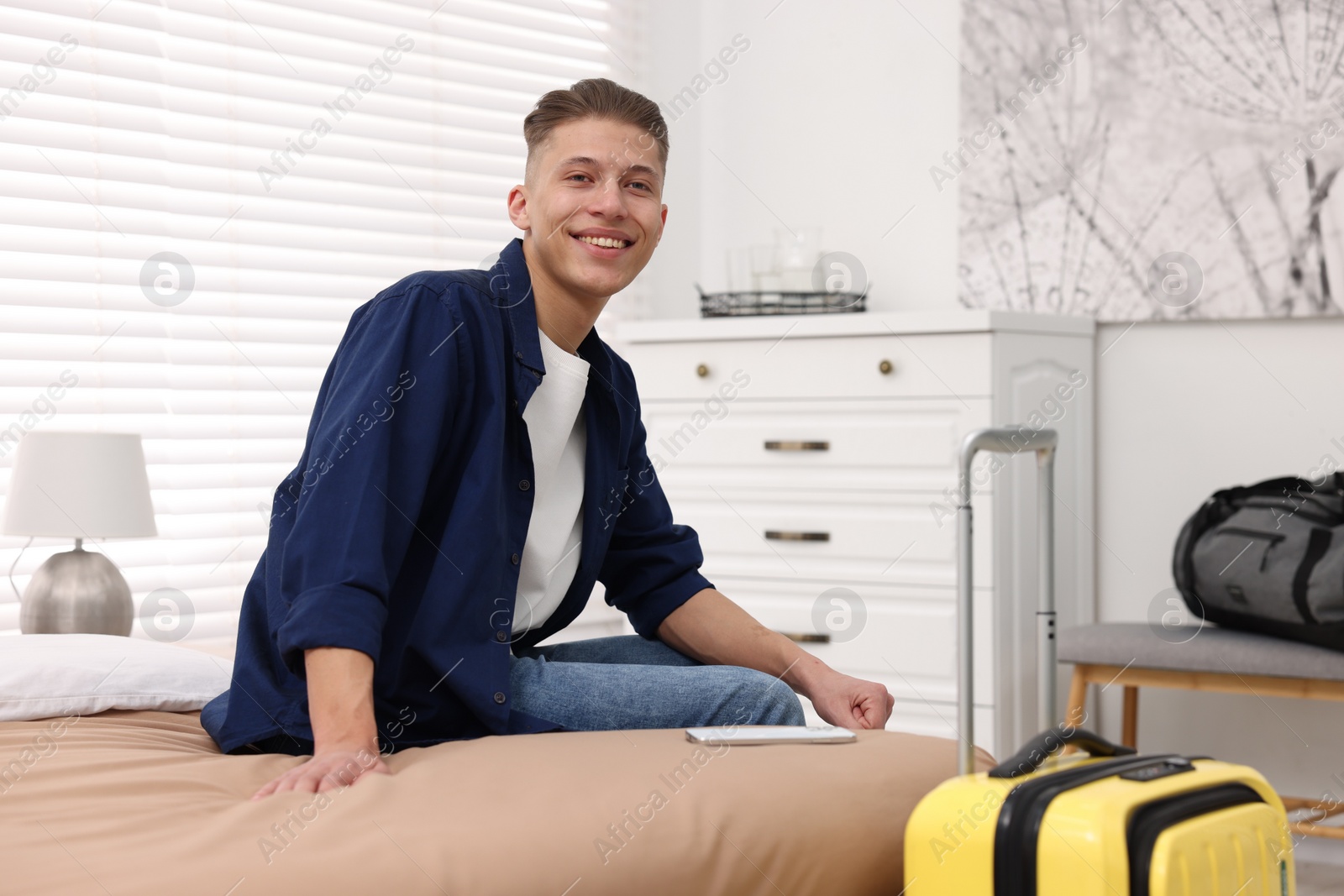 Photo of Smiling guest relaxing on bed in stylish hotel room