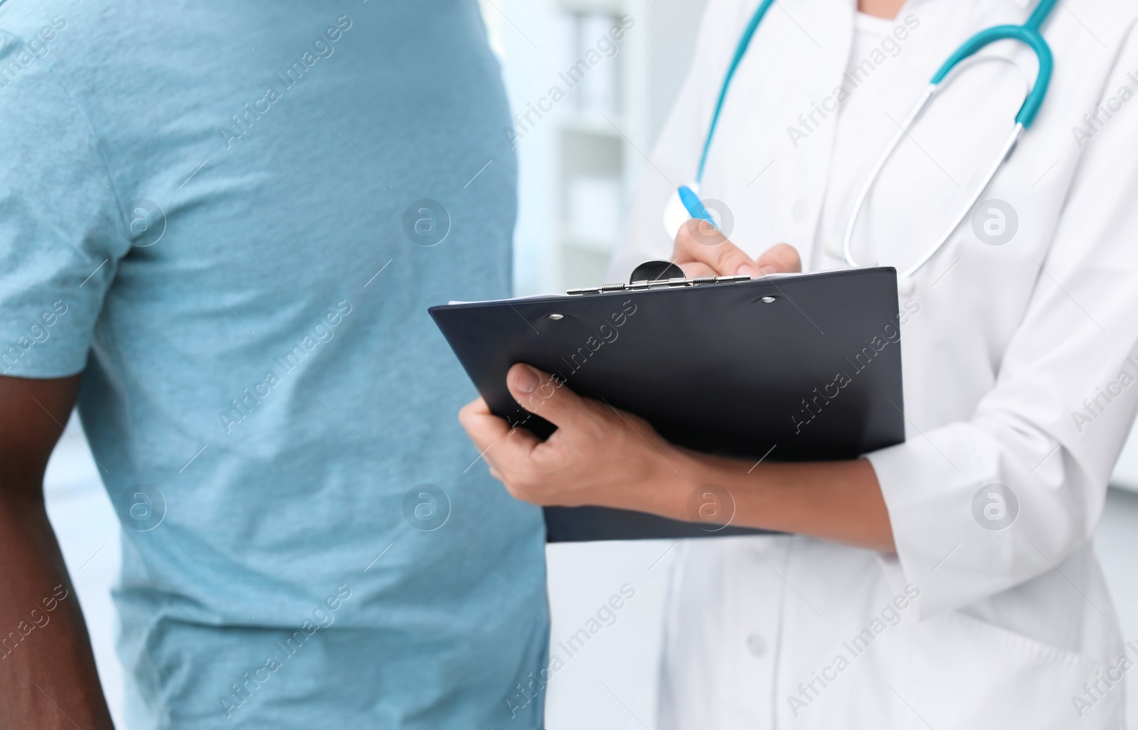 Photo of Young doctor consulting African-American patient in hospital